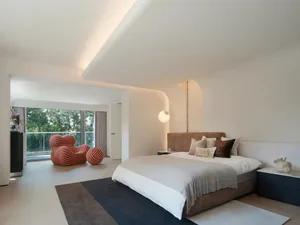 A modern minimalist bedroom with a neutral color palette featuring a large bed, plush pillows, and a sleek design.