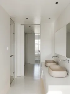 White minimalist bathroom with porcelain sinks and floors.