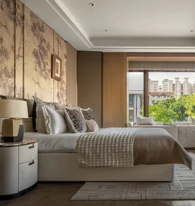 A modern residential bedroom featuring a contemporary bed with multiple pillows, a textured throw blanket, and a side table w