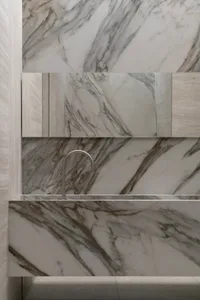 Modern minimalist bathroom featuring marble tiles and a sleek faucet.