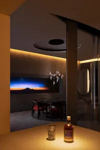 Modern, sleek living room with concrete walls and a large window showcasing a sunset.