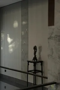 A modern interior space featuring marble walls adorned with floral wallpaper and a wooden pedestal with a sculptural decorati