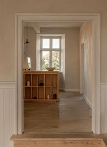 A modern corridor with wooden flooring and concrete walls.