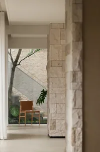 A living room featuring stone cladding walls, a wooden chair, and a green plant.