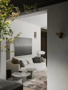 A modern minimalist living room featuring marble furniture and a large abstract artwork.