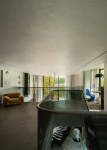 A spacious, modern living room featuring glass walls and polished concrete flooring.