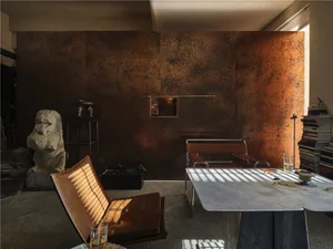 A living room featuring a metallic textured wall, a brown leather chair, and a table.