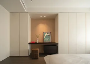 A minimalist bedroom with a bed, white bedding, a wooden desk, and a poster on the wall.