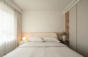 A minimalist bedroom with a neutral color palette, white bed, and simple furnishings.