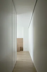 A minimalist hallway with wooden flooring and plain walls, showing a clean and uncluttered design.