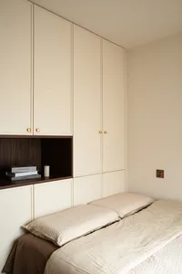 A minimalist bedroom with neutral tones and a single bed.