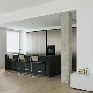 Modern black kitchen with concrete pillar and stainless steel appliances.