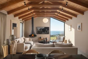 Modern living room with a wooden beam ceiling and a suspended fireplace.