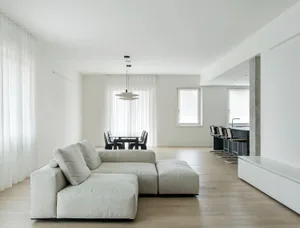 Modern minimalist living and dining room with concrete elements and a sleek, open layout.
