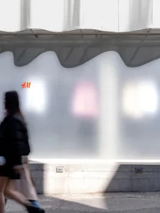 People walking past a modern storefront with glass walls.