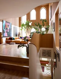 Modern living room with high ceilings, arched windows, wooden accents, and a comfortable seating area.