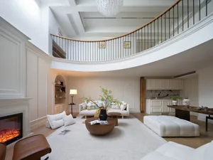 A minimalist living room with a white sofa, beige cushions, wooden coffee table, and soft textures, illuminated by natural li
