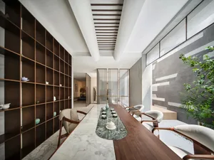 A minimalist living room with a wooden bench, marble table, and glass partitions. The space features a ceiling with exposed b