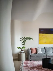 Contemporary living room with a modern sofa, minimalistic decor, and a potted fern.