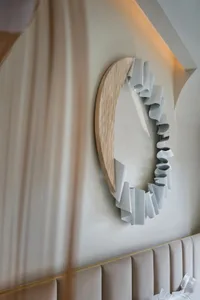 A modern, curved wooden wall object with white ribbons attached.
