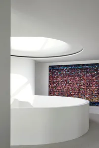 Modern interior design featuring sleek, white concrete walls and a large, abstract painting on the wall.