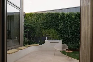 A minimalist residential patio area with a concrete floor and an ivy-covered exterior wall.