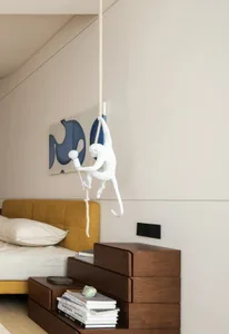 A modern bedroom featuring a wooden floating nightstand with books and a decorative seashell, a yellow upholstered bed, and a