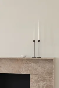 Minimalist marble fireplace with sculptural design and tall candlesticks