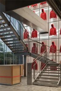 Retail store featuring a metal mesh display wall showcasing red hoodie sweatshirts.