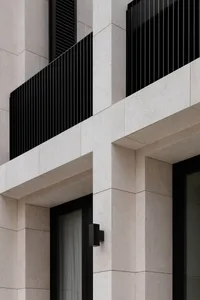 Modern building exterior with concrete, marble, black steel, and balconies.