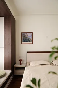 A modern minimalist bedroom featuring a headboard with a wooden frame and a white bedspread.