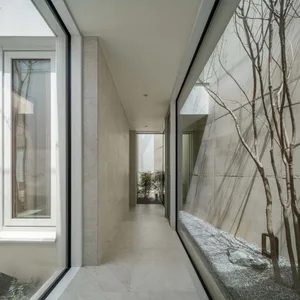 Modern white concrete corridor with a minimalist design, featuring glass walls and concrete walls