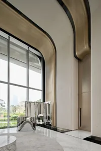 Modern hotel lobby with marble walls and floor, featuring sleek furniture and large windows.