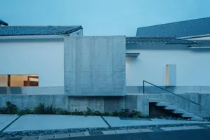 一座擁有混凝土外牆的大型窗戶與極簡設計的現代住宅建築。