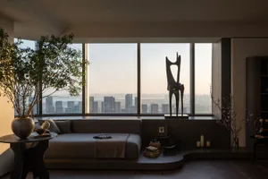 A modern apartment featuring a city view, with a comfortable seating area and decorative sculptures.