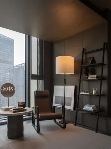 Luxurious modern living room featuring a bookshelf with eclectic items and a comfortable armchair.