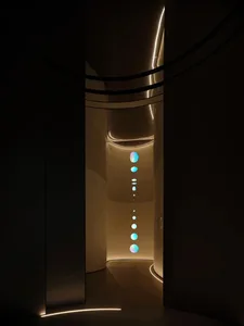 A minimalist interior space featuring illuminated curved glass panels and a line of glowing orbs.