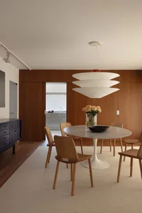 Modern dining room featuring wooden chairs and a marble table.