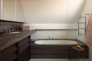 A minimalist modern bathroom with a granite countertop, double sink, and large soaking tub.