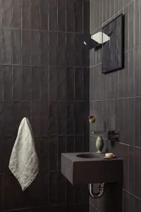 Concrete corner sink with a vase of flowers and a bar of soap in a minimalist bathroom setting.