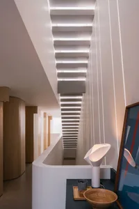 Modern interior with concrete staircase illuminated by a contemporary lamp.