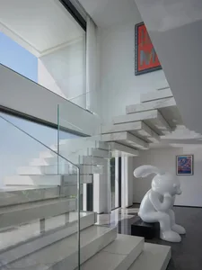Modern white marble and glass staircase in an interior design setting.