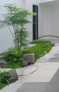現代簡約景觀設計，鋪面步道兩側以天然石材、泥炭苔及綠草點綴。