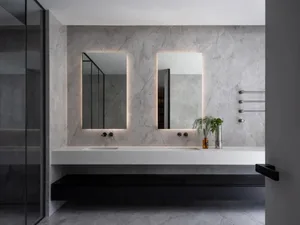 Modern bathroom with marble walls and flooring, featuring a minimalist design with floating vanity and double sinks.