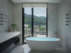 A modern marble bathroom with a large window overlooking hills and buildings.