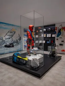A display featuring climbing gear and equipment, including a glass case and background mural of snowy mountains.
