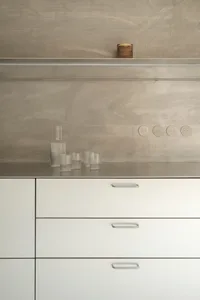 A modern kitchen featuring metallic cabinets and a concrete backsplash.