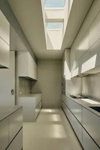 Modern white kitchen with concrete countertops and minimalist design.