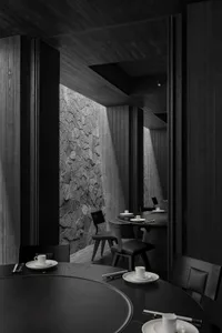 A modern minimalist restaurant interior with dark wooden and concrete materials.