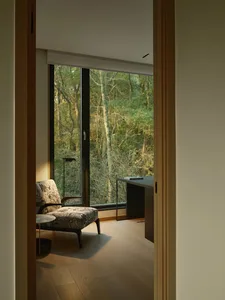Modern residential interior featuring a cozy seating area with a floral-patterned armchair and a wooden floor, with a view of